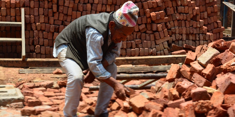 Ein Mann durchwühlt die Trümmer eines alten Hauses für den Wiederaufbau nach dem Erdbeben 2015 in Kathmandu